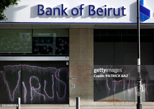 Graffiti reading "VIRUS" and "THIEF" covers the facade of a fortified local branch of the Bank of Beirut in the Lebanese capital on May 18, 2020. -...