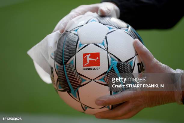 An employee of Werder Bremen disinfects an official match ball ahead of the German first division Bundesliga football match Werder Bremen v Bayer 04...