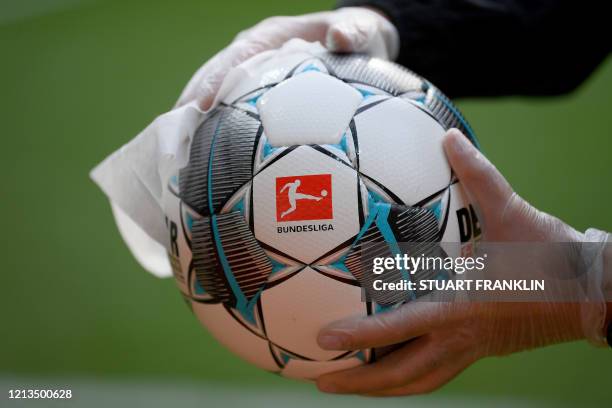 An employee of Werder Bremen disinfects an official match ball ahead of the German first division Bundesliga football match Werder Bremen v Bayer 04...