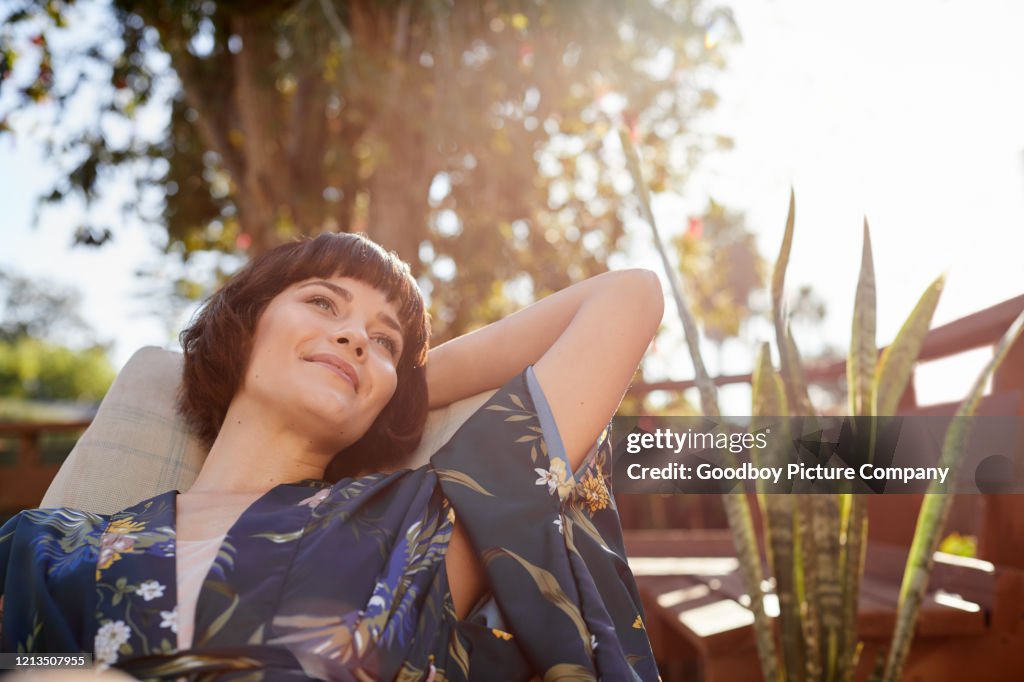 Smiling young woman lying back in a patio deck chair