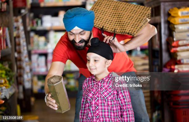 vater und sohn lebensmitteleinkauf im supermarkt - sikhism stock-fotos und bilder