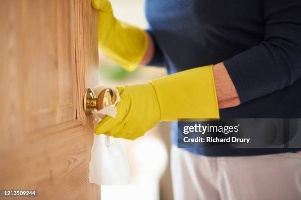 mature woman wiping down a doorknob - cleaning doorknob stock pictures, royalty-free photos & images