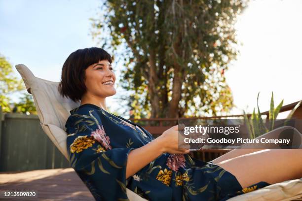 leende ung kvinna realxing utanför med en kopp te - däcksstol bildbanksfoton och bilder