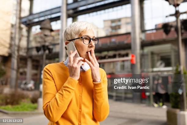 elderly woman using a mobile phone - female worried mobile imagens e fotografias de stock