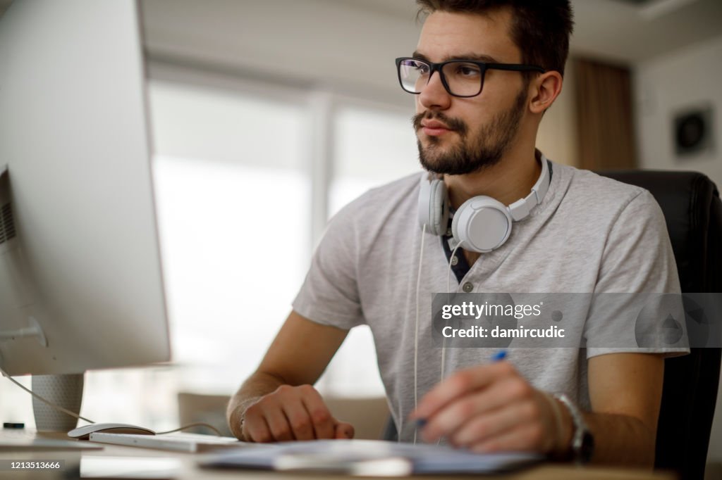 Young Man Using Computer And Taking Notes High-Res Stock Photo - Getty ...