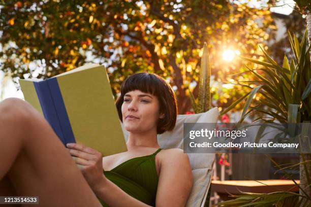 young woman in a swimsuit reading a book on her patio - reading outside stock pictures, royalty-free photos & images