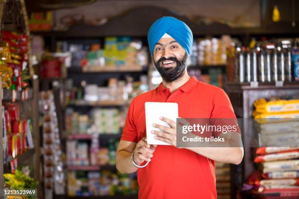 man with digital tablet at grocery store - sikhism stock pictures, royalty-free photos & images