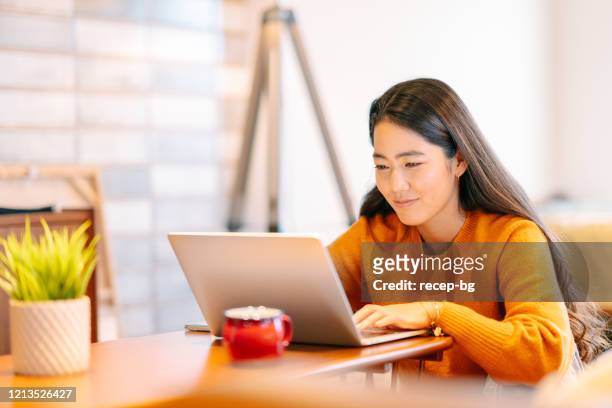 mujer joven usando portátil cómodamente en casa - sólo con adultos fotografías e imágenes de stock