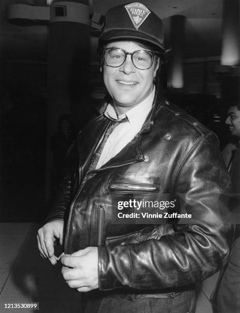 Canadian actor and comedian Dan Aykroyd at Los Angeles airport en route to New York, circa 1990. He is wearing a Massachusetts State Police cap.