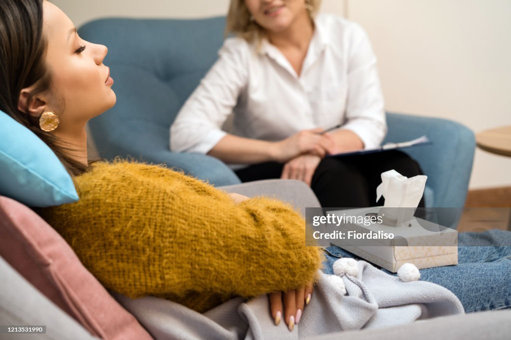 Positive blonde middle-aged woman psychologist talking to girl patient