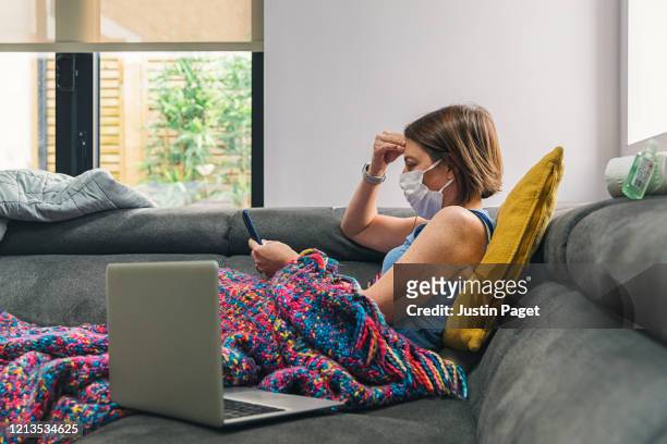 woman self isolating on the sofa with flu - pandemic illness stock pictures, royalty-free photos & images