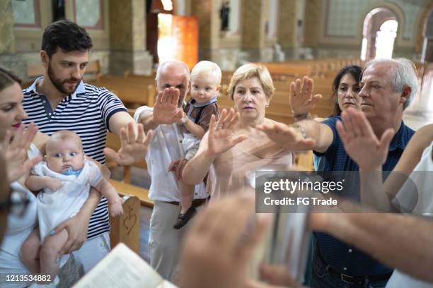 familie betet in der kirche - catholic baptism stock-fotos und bilder