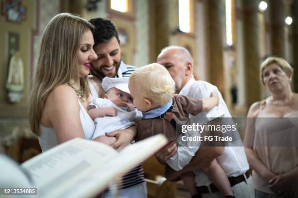 eltern und sein sohn bei tauffeier in der kirche - catholic baptism stock-fotos und bilder