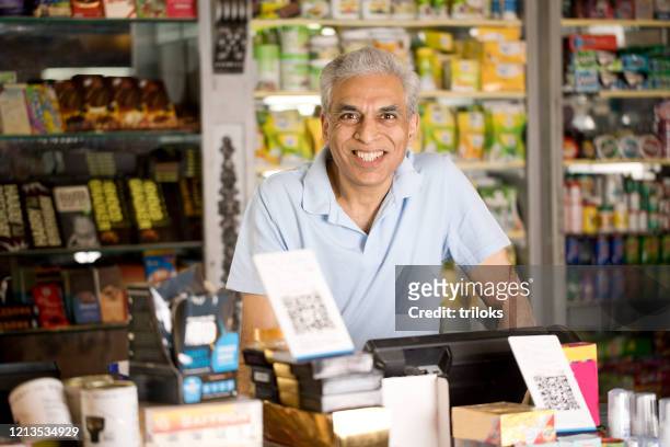 propriétaire masculin au supermarché - indian market photos et images de collection
