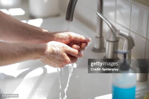 man washing his hands at the kitchen sink - rubbing hands closeup stock pictures, royalty-free photos & images