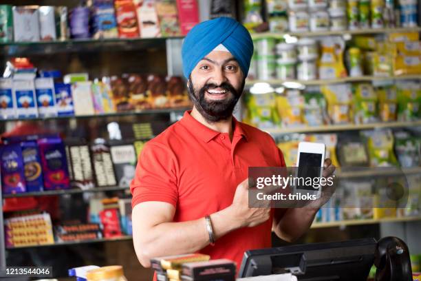 快樂雜貨店老闆拿著信用卡讀卡機 - convenient store 個照片及圖片檔