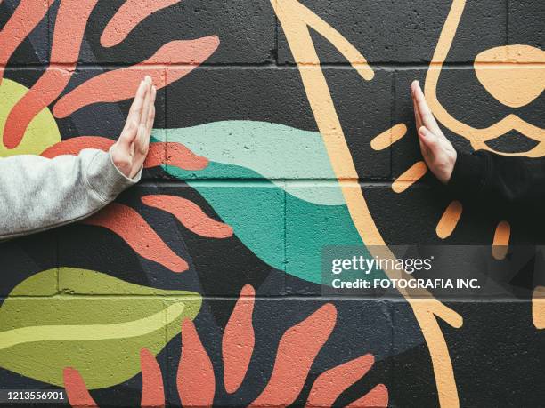 covid-19 social distancing, teenagers' hands against mural wall - streetart imagens e fotografias de stock