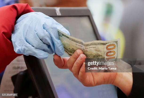 Woman pays cash while wearing gloves during special hours open only to seniors and the disabled at Northgate Gonzalez Market, a Hispanic specialty...