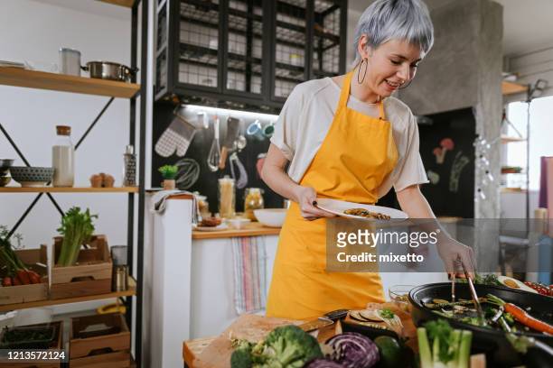 beautiful woman preparing vegetarian lunch at modern kitchen at home - one person cooking stock pictures, royalty-free photos & images