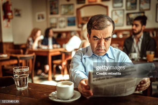 man with dwarfism reading newspaper at cafe - dwarf stock pictures, royalty-free photos & images