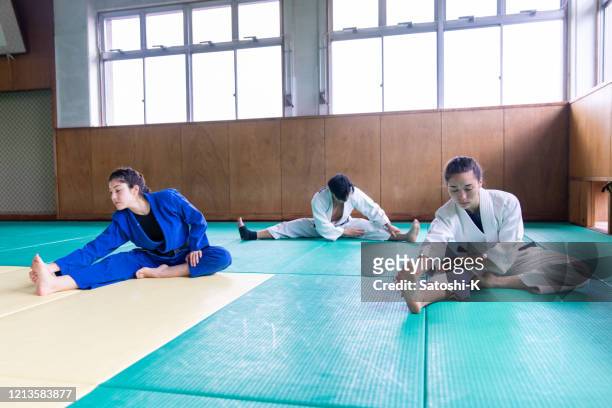 three judo athletes stretching in dojo - judo female stock pictures, royalty-free photos & images