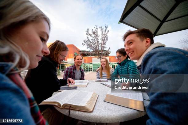 een groep studenten die een bespreking hebben en de bijbel bestuderen - book club meeting stockfoto's en -beelden