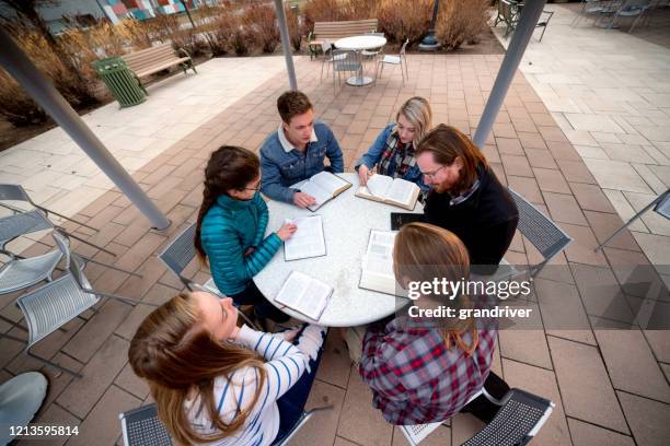 een groep studenten die een bespreking hebben en de bijbel bestuderen - bible society stockfoto's en -beelden