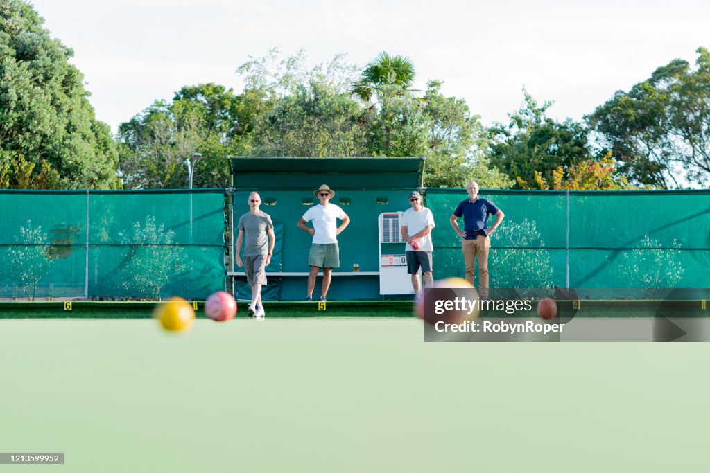 Senior friends playing social lawn bowls outdoors
