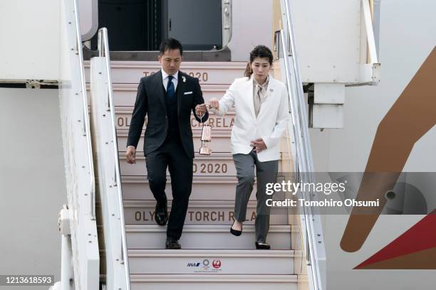 Olympic gold medalists Tadahiro Nomura and Saori Yoshida holding the Olympic flame walk down an passenger boarding stairs during the Tokyo 2020...