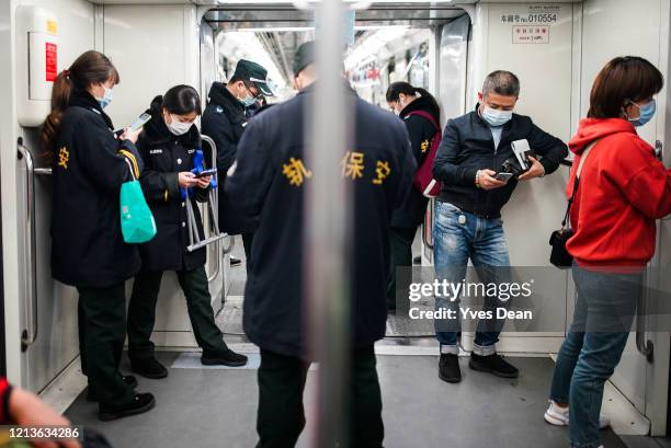 Security workers of Shanghai subway and passengers wear protective masks while riding a subway train on March 20, 2020 in Shanghai, China. Health...