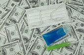 Doctor mask and virus protection alcohol gel bottle and money a stack of 100 US dollars banknote a lot of, That was It costs expensive price and high priced products concept