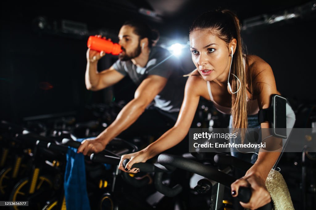 Two young people exercising on exercise bike at gym