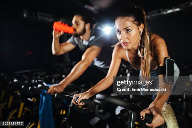 two young people exercising on exercise bike at gym - cycling gym stock pictures, royalty-free photos & images