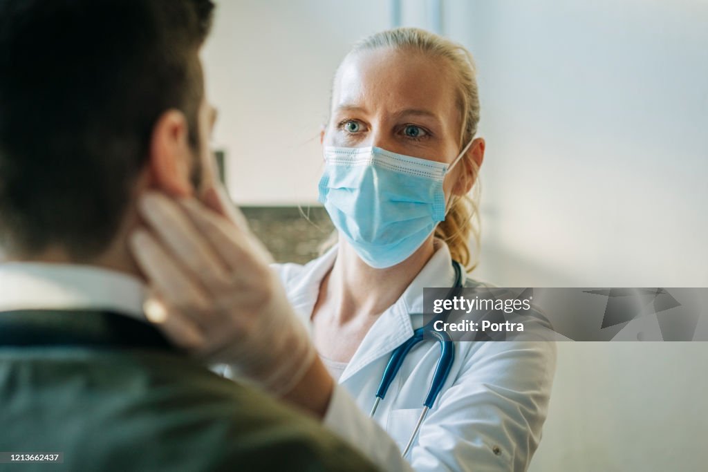 Doctor wearing surgical mask examining man