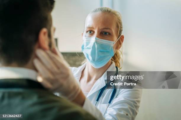 doctor wearing surgical mask examining man - hospital safety stock pictures, royalty-free photos & images