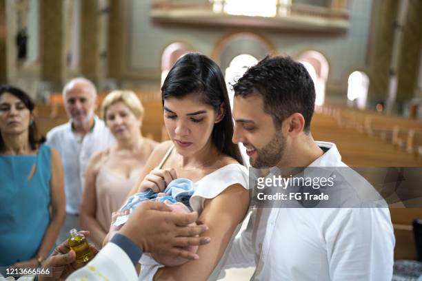 padrinhos com um bebê afilhado na celebração do batismo - catholic baptism - fotografias e filmes do acervo