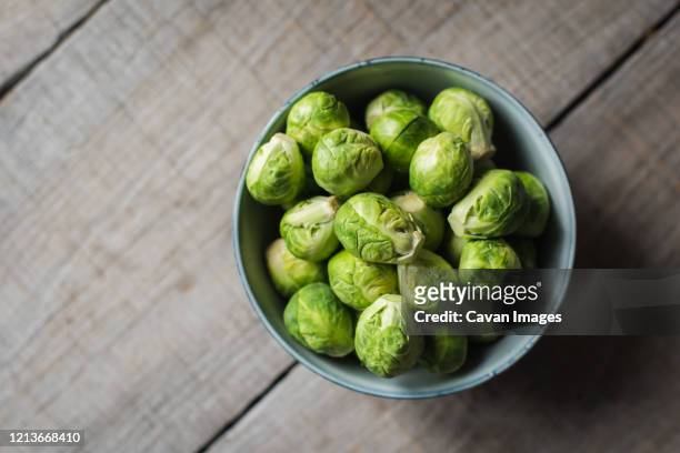 overhead view of bowl of brussels sprouts on wooden background. - brussel sprout stock pictures, royalty-free photos & images