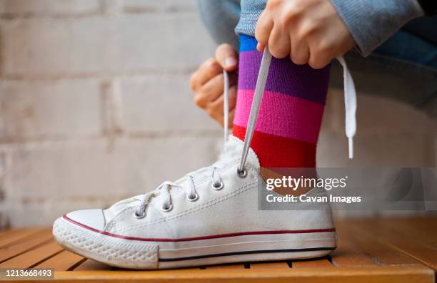 woman tying laces of her white sneaker. - shoelace fotografías e imágenes de stock