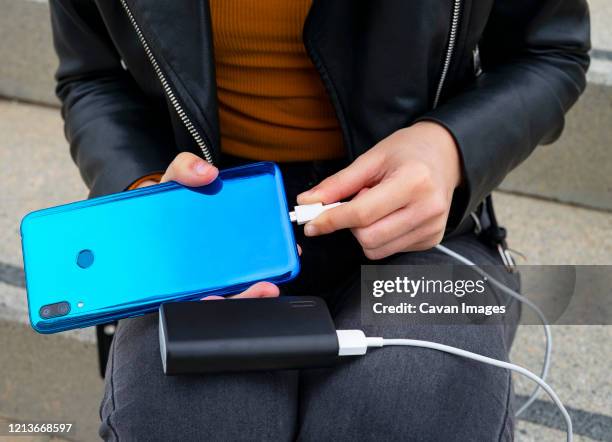 woman connecting the mobile to a powerbank. - powerbank stock-fotos und bilder