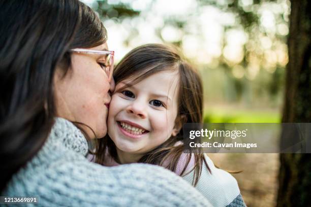close up view of mother kissing and hugging young cute daughter. - surrey british columbia stock pictures, royalty-free photos & images