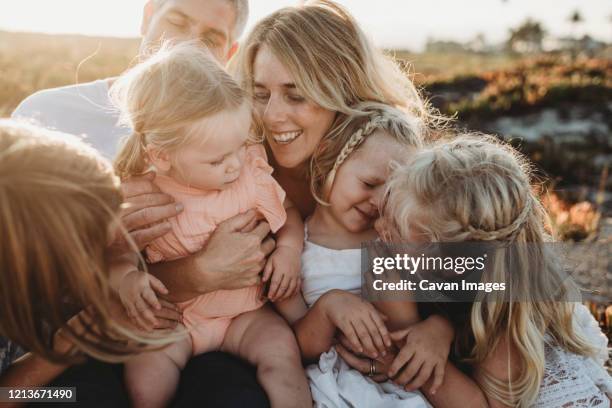 lifestyle close up of family with young sisters sitting on beach - familie mit vier kindern stock-fotos und bilder