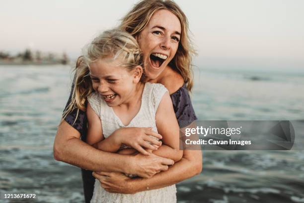 mother embracing young girl with freckles in ocean laughing - kids laughing close up stock pictures, royalty-free photos & images