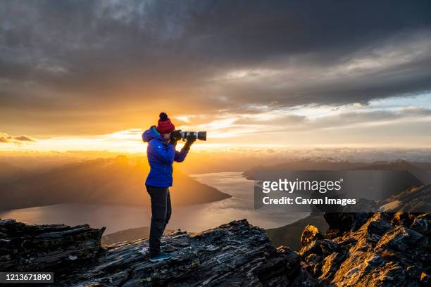 figure with camera above queenstown and lake, remarkables new zeala - kearton stock-fotos und bilder