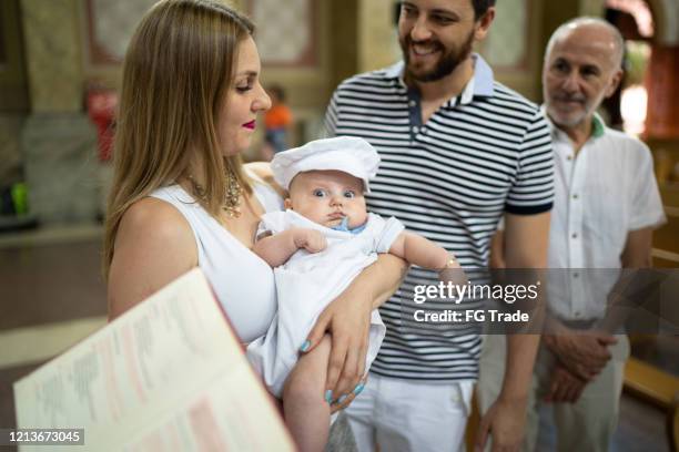 pais e seu filho em celebração de batismo na igreja - catholic baptism - fotografias e filmes do acervo