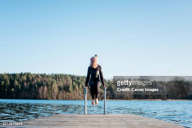 woman about to jump into cold ice water whilst at the beach in sweden - do it stock pictures, royalty-free photos & images
