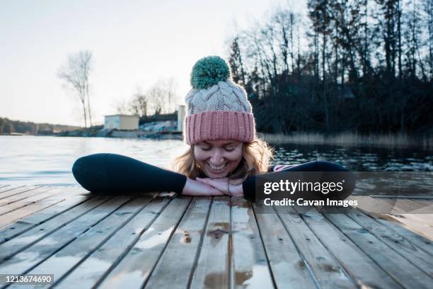 woman smiling leaning on a jetty whilst in the sea cold water swimming - woman swimming stock pictures, royalty-free photos & images