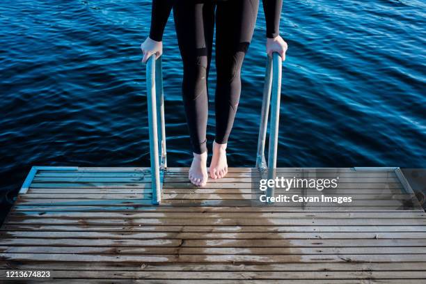 woman's feet standing on steps down to cold water for swimming - do it stock pictures, royalty-free photos & images