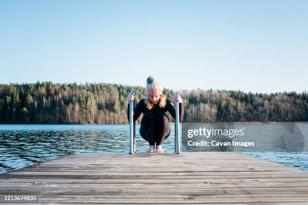 woman preparing to go swimming in cold water at a beach in winter - eis baden stock-fotos und bilder