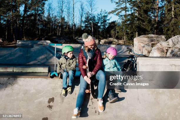 mom and her kids playing at a skate park outside in the sunshine - mother and daughter riding on skateboard in park stock pictures, royalty-free photos & images