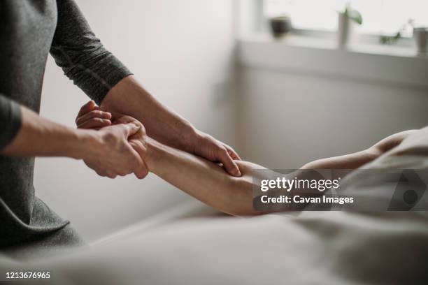 close up of massage therapist treating patient's bicep - jambes hommes photos et images de collection